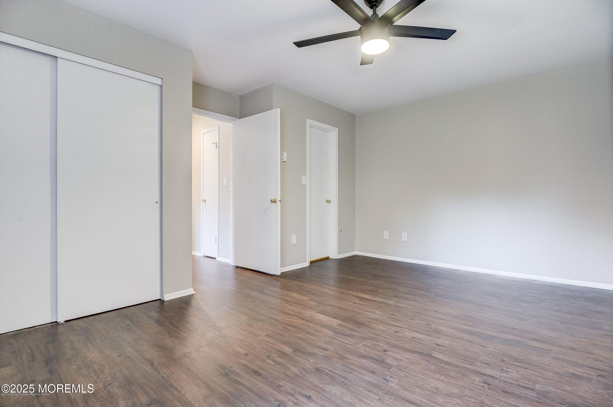 97 Arrowood Road, Unit K Manalapan, NJ 07726 - Photo 12 of 29 a view of an empty room with wooden floor and a ceiling fan