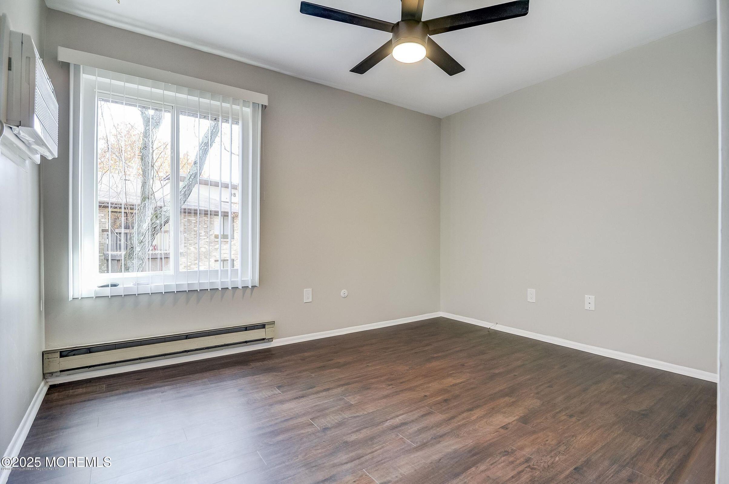 97 Arrowood Road, Unit K Manalapan, NJ 07726 - Photo 16 of 29 an empty room with wooden floor and windows