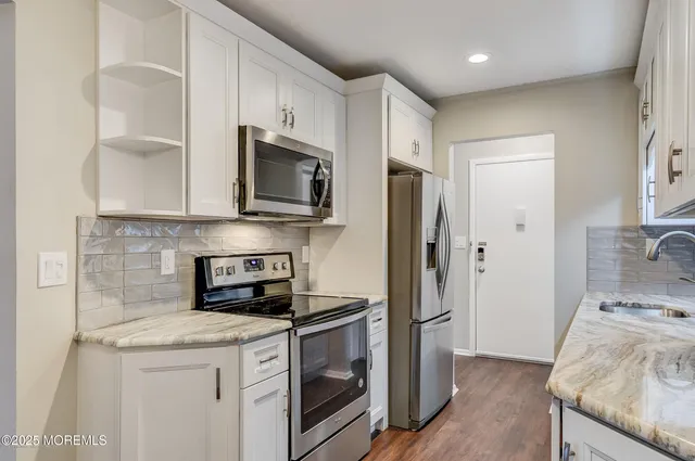 a kitchen with stainless steel appliances granite countertop a refrigerator and a stove top oven