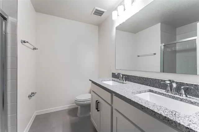 a bathroom with a granite countertop sink a toilet and a mirror