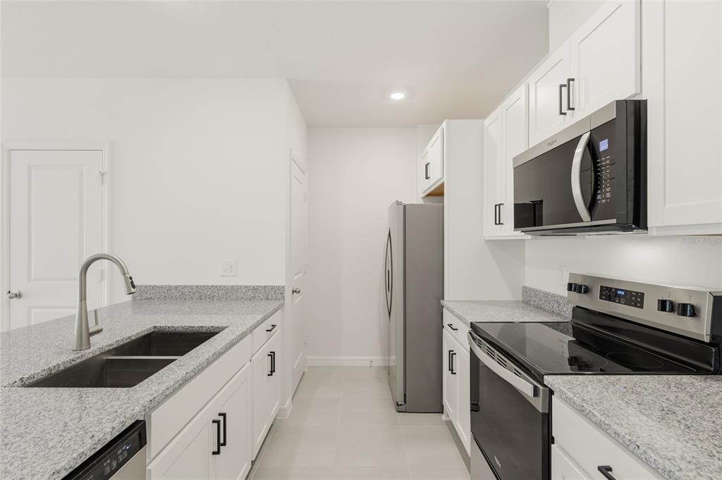 2770 Raindrop Run Street Clermont, FL 34714 - Photo 3 of 28 a kitchen with stainless steel appliances granite countertop a sink stove and refrigerator