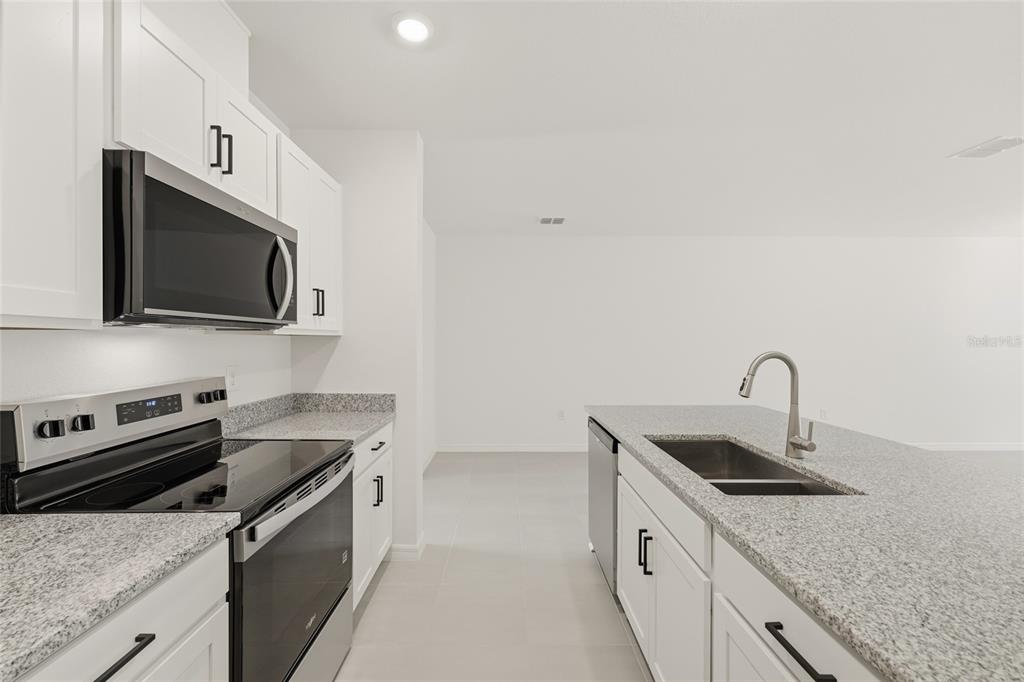 2770 Raindrop Run Street Clermont, FL 34714 - Photo 4 of 28 a kitchen with granite countertop a sink dishwasher stove and microwave with wooden floor
