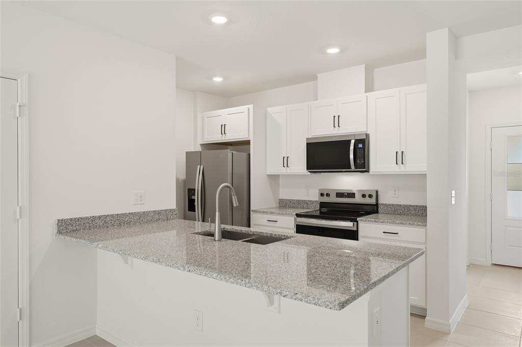 2770 Raindrop Run Street Clermont, FL 34714 - Photo 6 of 28 a kitchen with stainless steel appliances granite countertop a sink stove and refrigerator