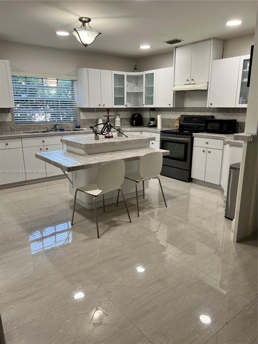 6284 Southwest 26th Street Miami, FL 33155 - Photo 19 of 25 a kitchen with stainless steel appliances kitchen island granite countertop a stove a sink a counter space and cabinets
