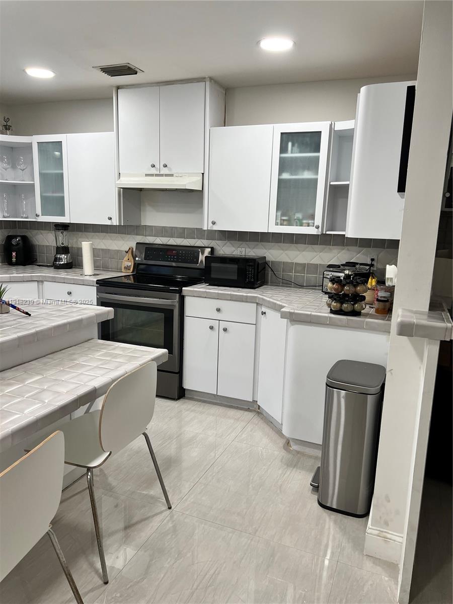 6284 Southwest 26th Street Miami, FL 33155 - Photo 20 of 25 a kitchen with a sink a stove a refrigerator and cabinets