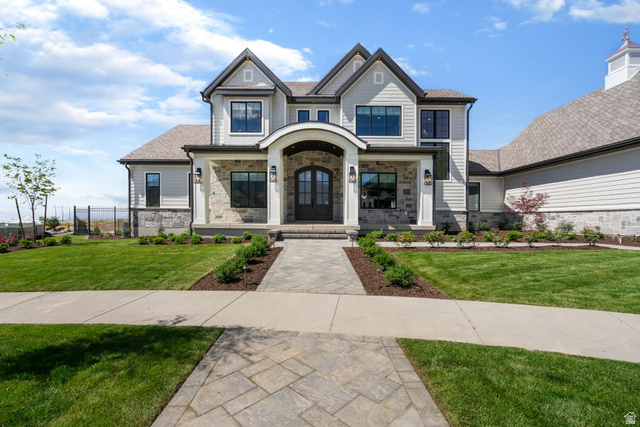115 East Hidden Ridge Lane, Unit 42 Mapleton, UT 84664 - Photo 102 of 103 Contemporary residence featuring a stone and siding exterior, arched entry with double doors, paved walkway, and a manicured lawn with mature landscaping