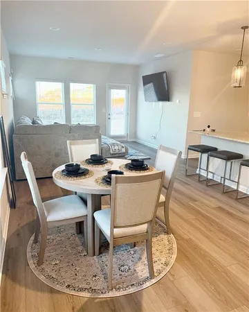 a dining room with wooden floor a glass table and chairs