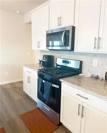 a kitchen with granite countertop a stove microwave and sink