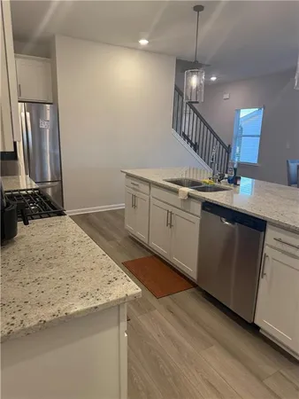 a kitchen with granite countertop a sink a counter space appliances and cabinets