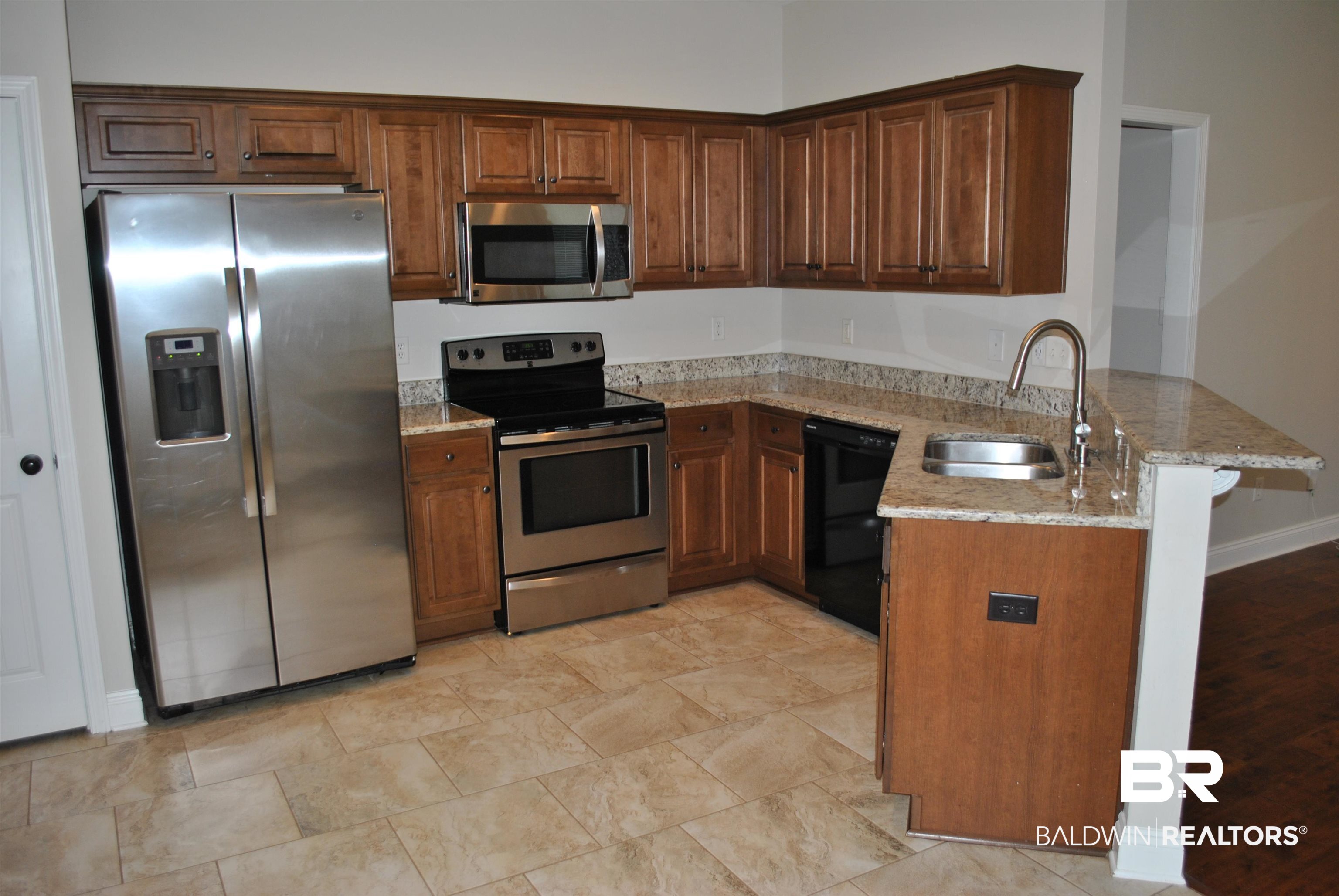 2161 Spring Grove West Mobile, AL 36695 - Photo 12 of 31 Kitchen featuring stainless steel appliances, a peninsula, light stone countertops, and brown cabinetry