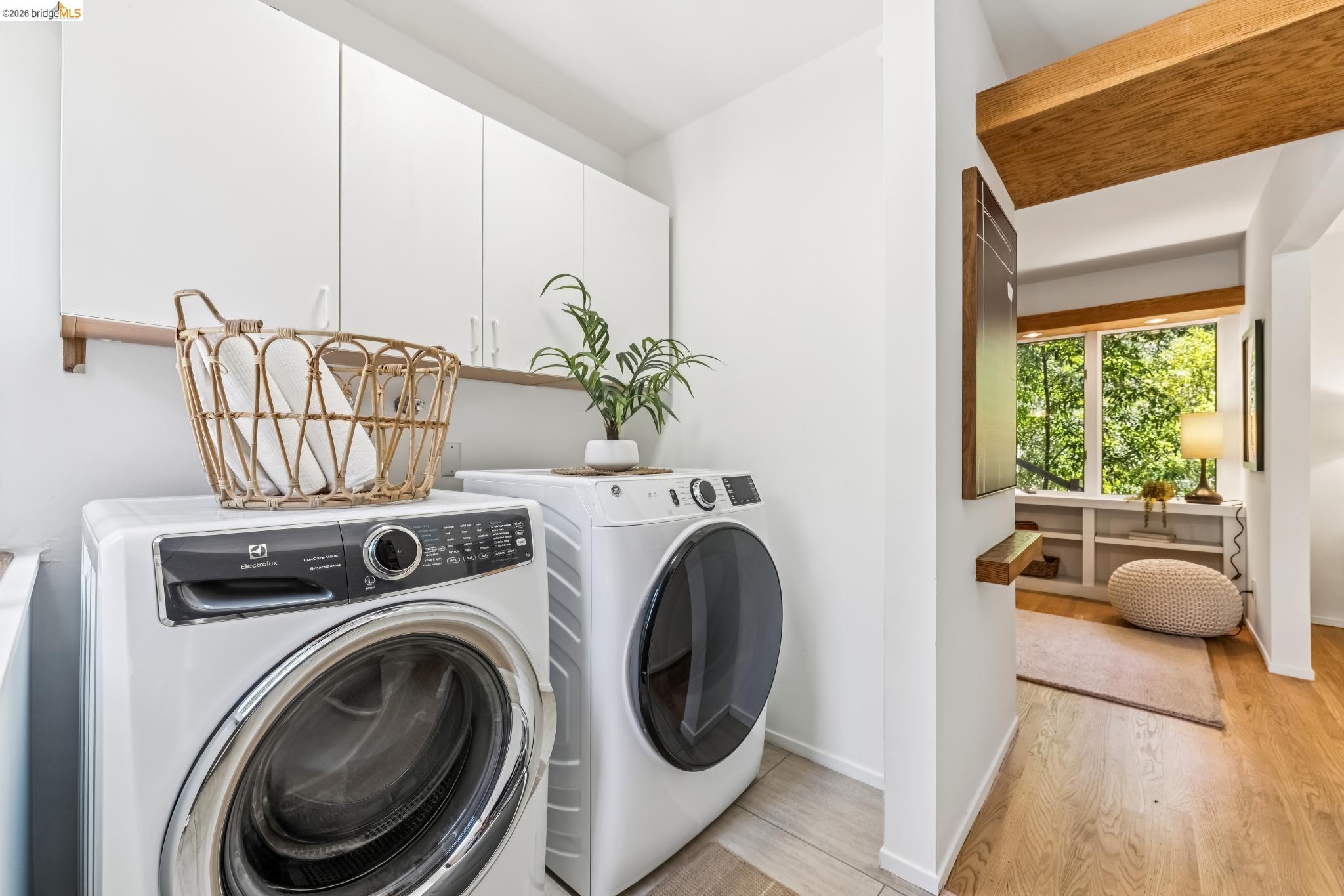 6645 Heather Ridge Way Oakland, CA 94611 - Photo 49 of 61 Dedicated laundry area featuring white upper cabinetry, a wood-finish wall shelf, and wood-finish flooring