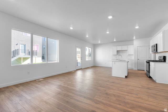 788 West 2840 South, Unit 2 Logan, UT 84321 - Photo 7 of 21 Open-concept living area featuring wood-finish flooring, recessed lighting, and a kitchen with white cabinetry