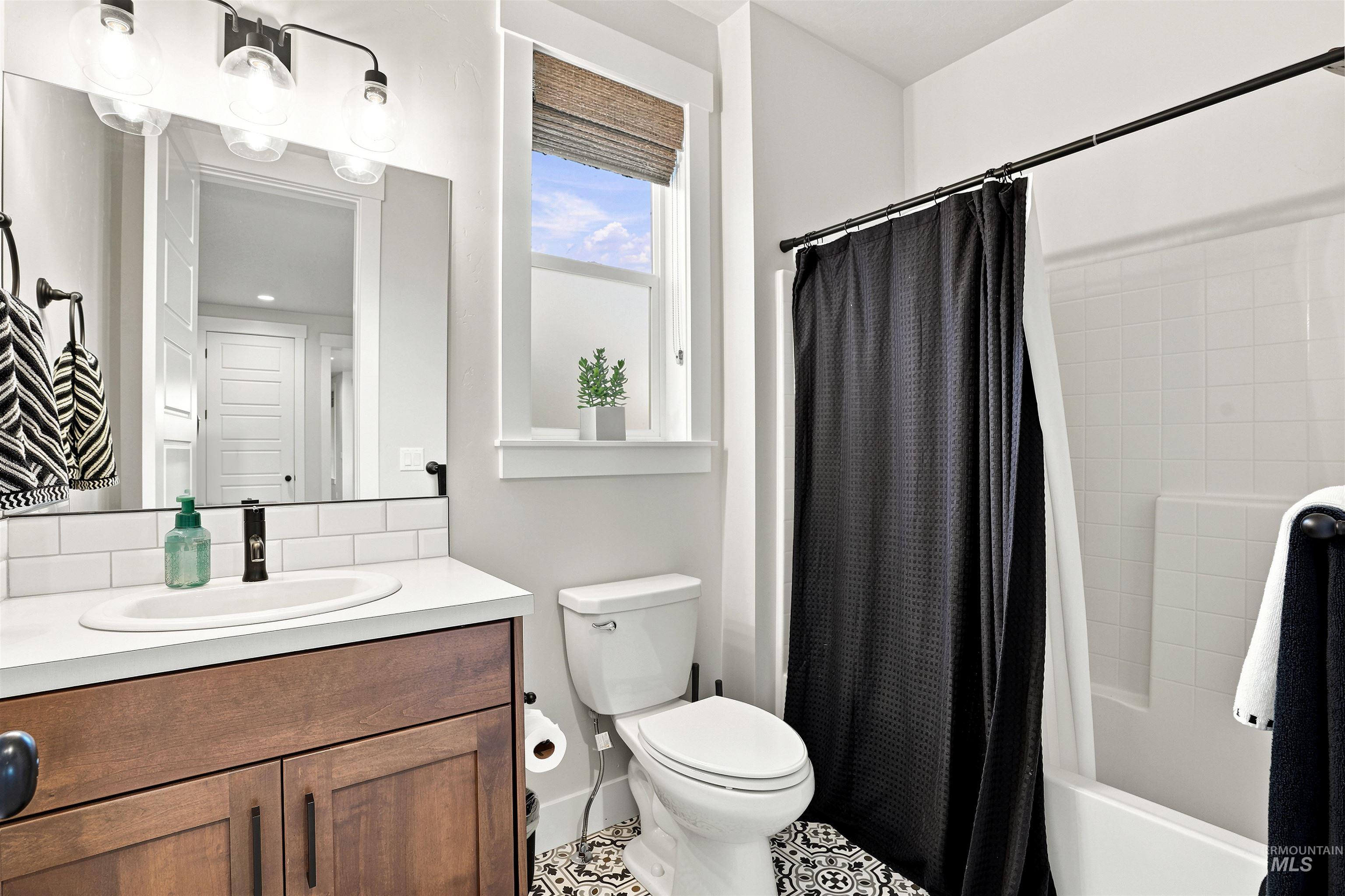 4323 West Ladle Rpds Drive Meridian, ID 83646 - Photo 29 of 49 Bathroom featuring a wood vanity with a white countertop, subway tile backsplash, and an undermount sink