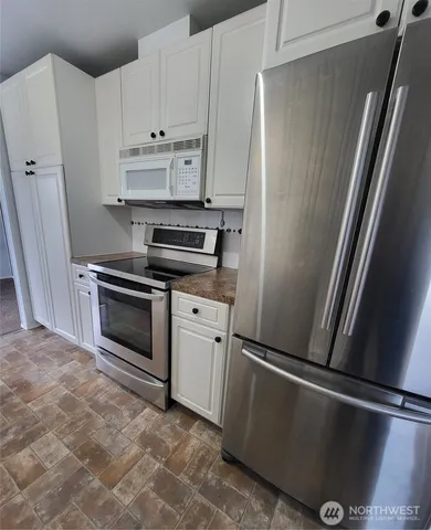 a kitchen with white cabinets and stainless steel appliances