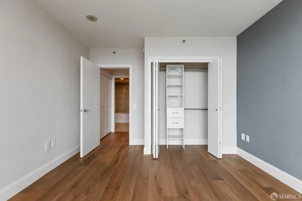 a view of an empty room with wooden floor and closet
