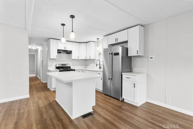 a kitchen with stainless steel appliances a refrigerator a stove a sink dishwasher and a refrigerator with wooden floor