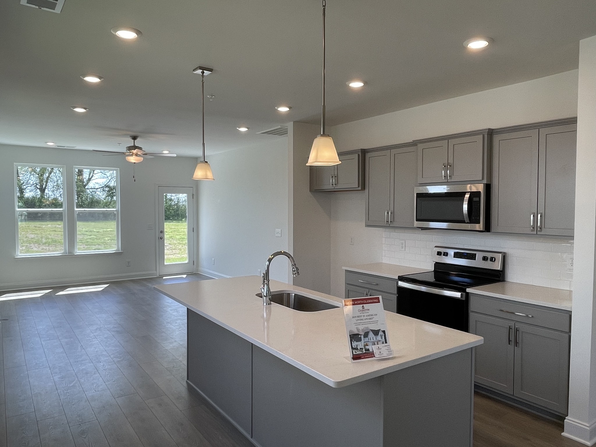 1156 June Wilde Ridge Spring Hill, TN 37174 - Photo 2 of 20 a kitchen that has a sink a microwave oven a stove and white cabinets with wooden floor
