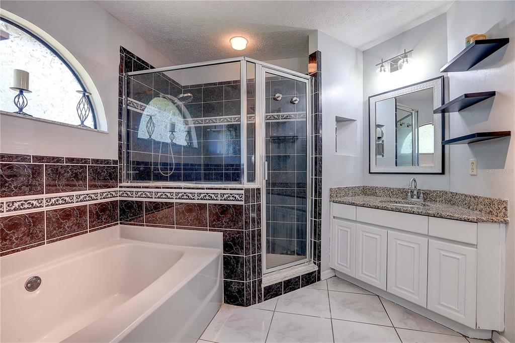 1418 Buckner Road Valrico, FL 33596 - Photo 13 of 37 a bathroom with a granite countertop sink a mirror a vanity and bathtub