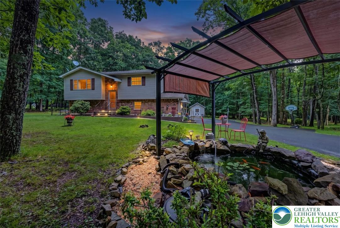 386 Upper Rdg Drive Effort, PA 18330 - Photo 51 of 56 A tranquil backyard oasis featuring a pergola and a charming koi pond, surrounded by verdant trees.