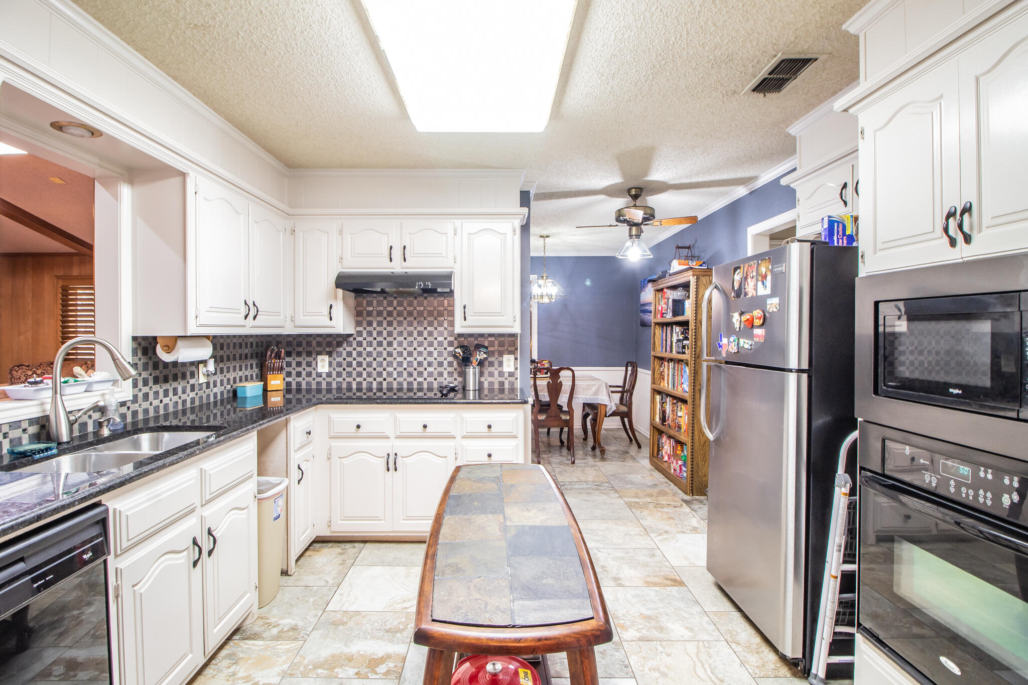 4213 88th Place Lubbock, TX 79423 - Photo 9 of 40 a large kitchen with stainless steel appliances granite countertop a refrigerator a stove a sink dishwasher and white cabinets with wooden floor