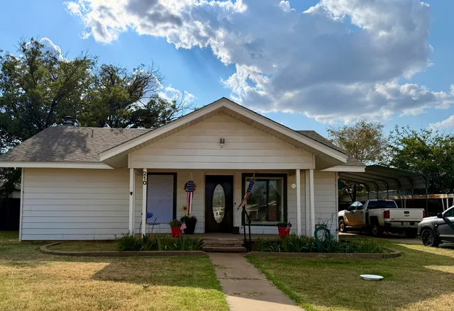 a view of a house with a small yard plants and large tree