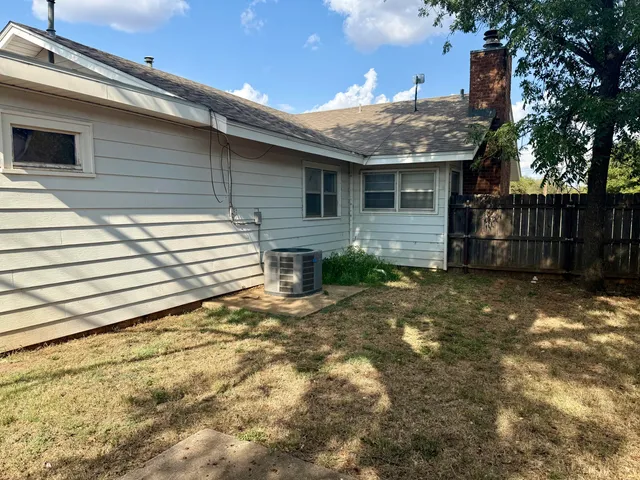 a view of patio with a table and chairs under an umbrella with a small yard