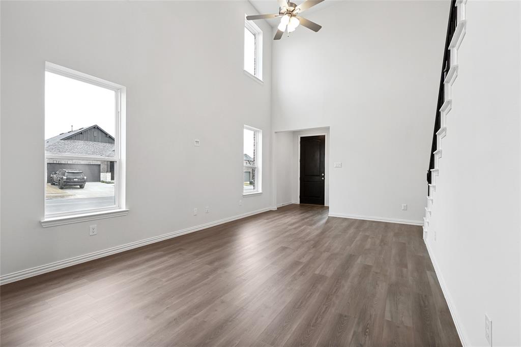 3900 Coco Lane Sherman, TX 75090 - Photo 5 of 40 Unfurnished living room with ceiling fan, wood-type flooring, and a towering ceiling