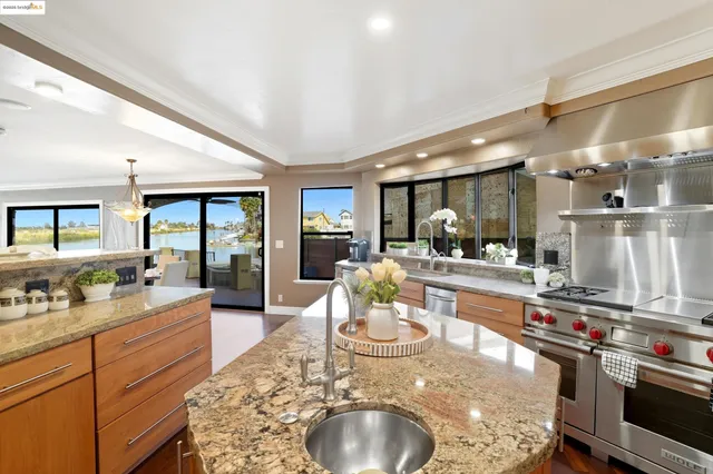 a room with stainless steel appliances kitchen island granite countertop a sink and cabinets