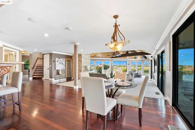 a dining room with wooden floor a chandelier a glass table and chairs