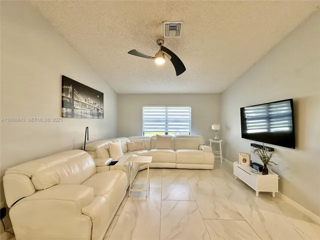 a living room with furniture ceiling fan and a window