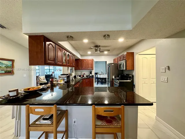 a kitchen with stainless steel appliances granite countertop a refrigerator a stove and a sink