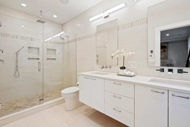 a bathroom with a double vanity sink toilet and shower