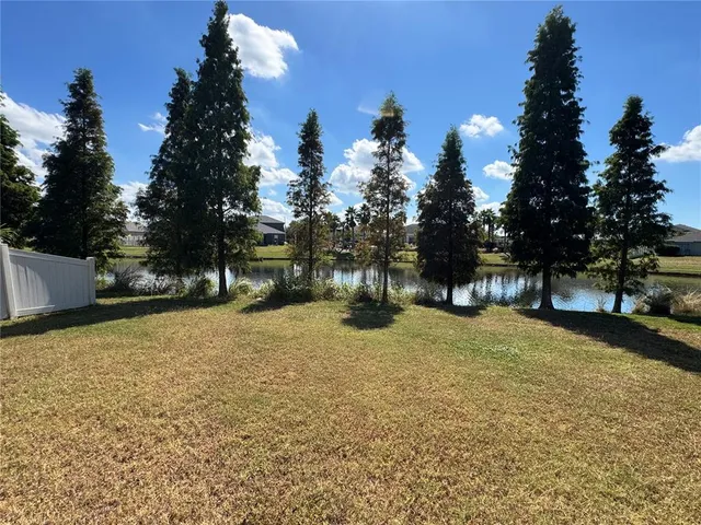 a tall yellow house with trees in the background