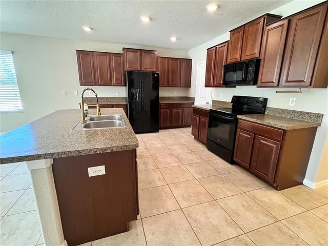 a kitchen with granite countertop a refrigerator a stove top oven a sink and dishwasher
