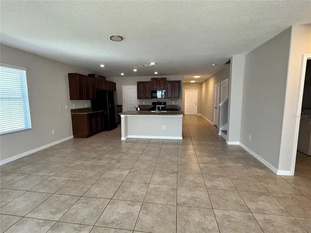 a view of a kitchen with kitchen island granite countertop a refrigerator stove top oven and sink