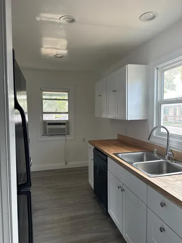 a utility room with stainless steel appliances granite countertop a sink and a refrigerator
