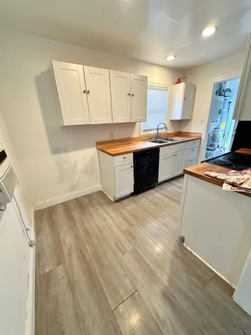a large kitchen with stainless steel appliances wooden floors and white walls