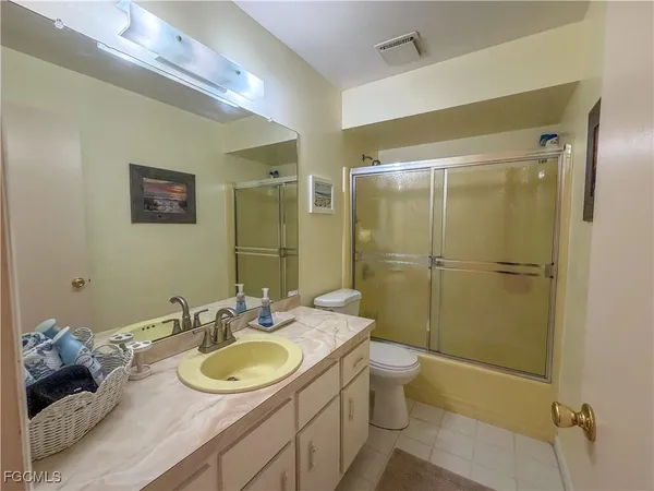 a bathroom with a granite countertop sink a toilet a mirror and shower