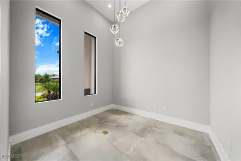 an empty room with a chandelier fan and windows