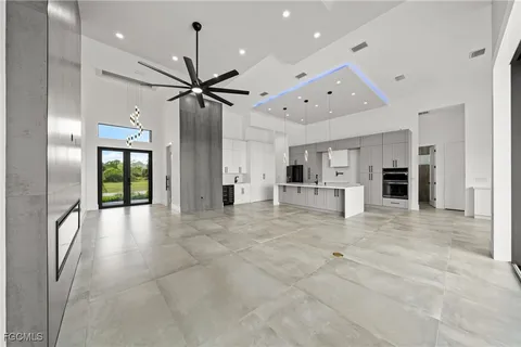 a view of a livingroom with a chandelier fan and kitchen view