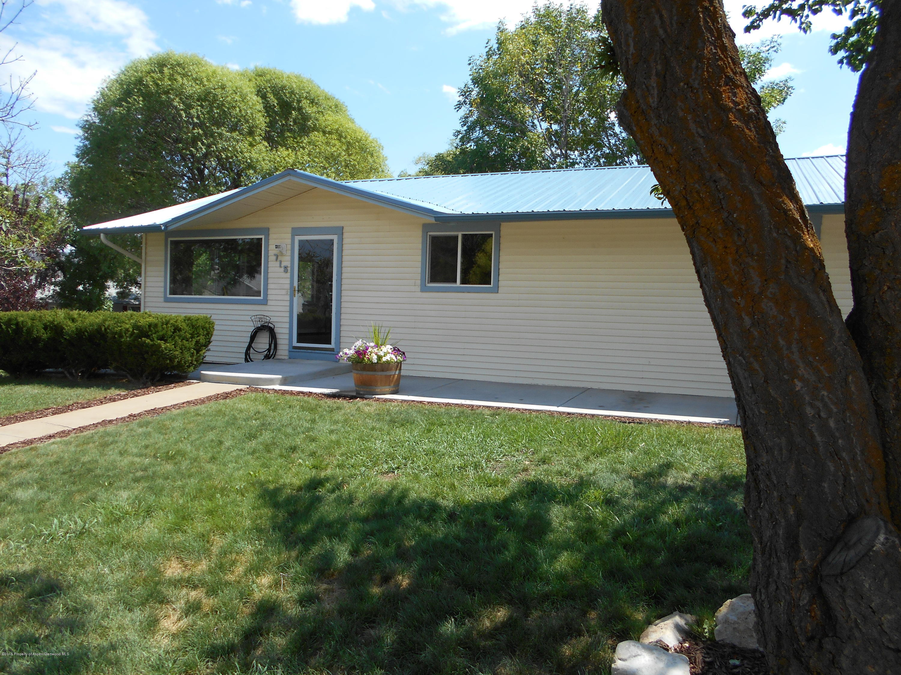 715 West 5th Street Rifle, CO 81650 - Photo 1 of 11 a backyard of a house with table and chairs plants and large tree