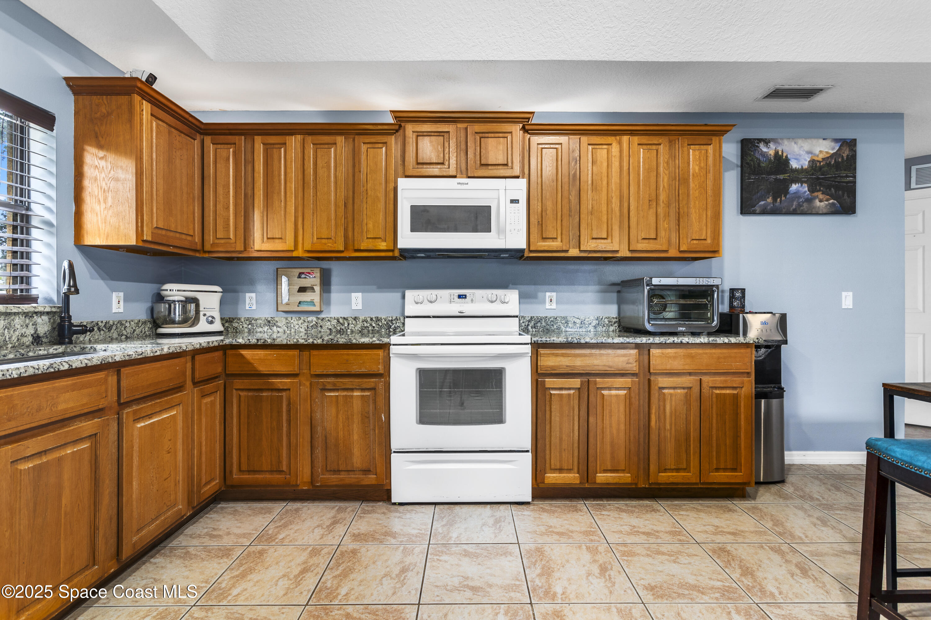 5964 Travis Street Mims, FL 32754 - Photo 26 of 45 a kitchen with granite countertop a stove top oven sink and cabinets