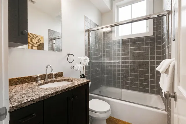 a bathroom with a granite countertop sink a toilet and shower