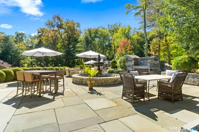a view of a patio with dining table and chairs under an umbrella with a barbeque grill and couches