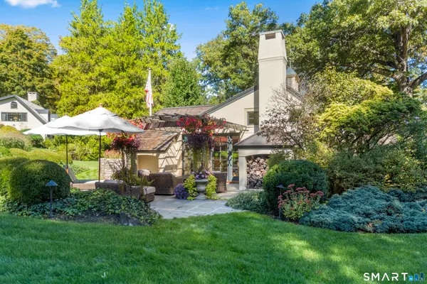 a view of a house with a large windows and a yard with plants and large trees