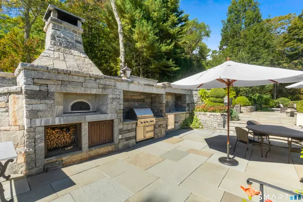 a view of a patio with table and chairs under an umbrella with a fireplace