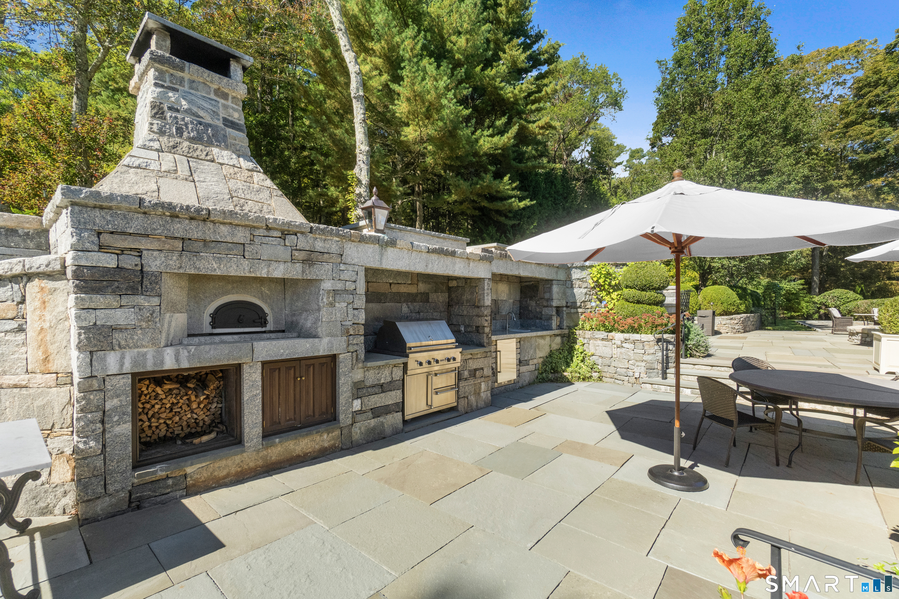 252 River Road Deep River, CT 06417 - Photo 5 of 40 a view of a patio with table and chairs under an umbrella with a fireplace