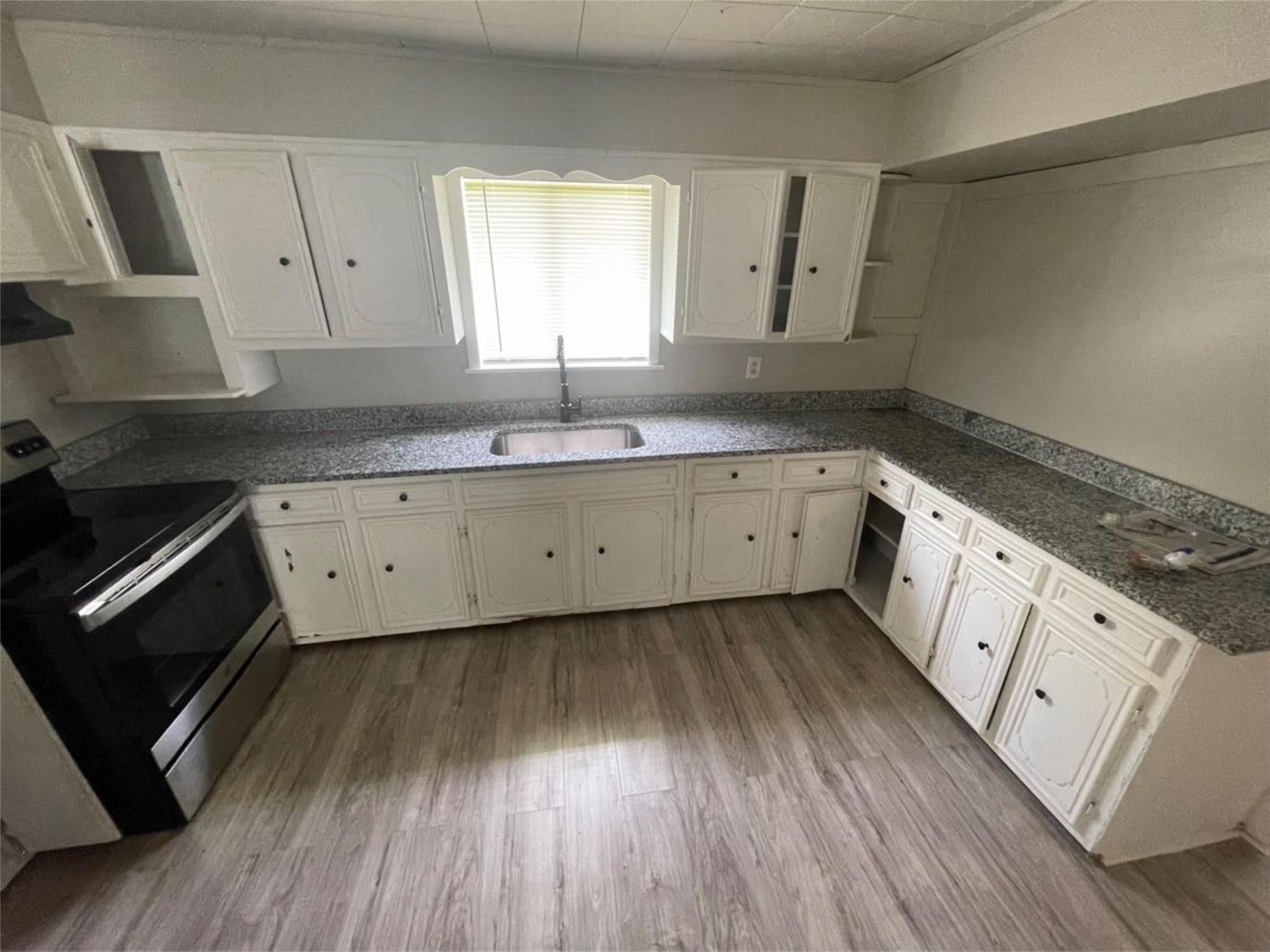 2010 13th Street Port Arthur, TX 77640 - Photo 11 of 22 a kitchen with wooden floors and white cabinets