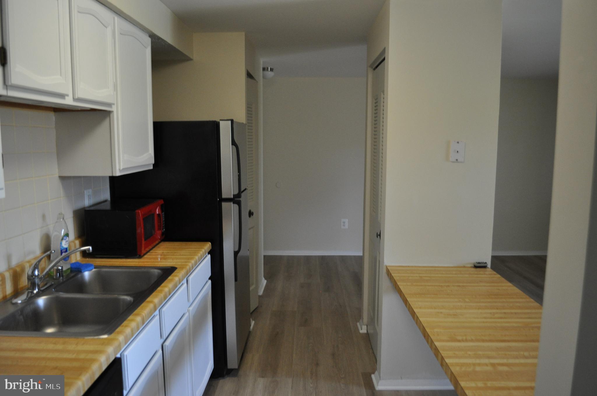 650 Heather Ridge Drive, Unit 12L Frederick, MD 21702 - Photo 5 of 20 a kitchen with kitchen island a sink wooden floor and a refrigerator