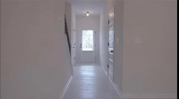 a view of a hallway with wooden floor and a bathroom
